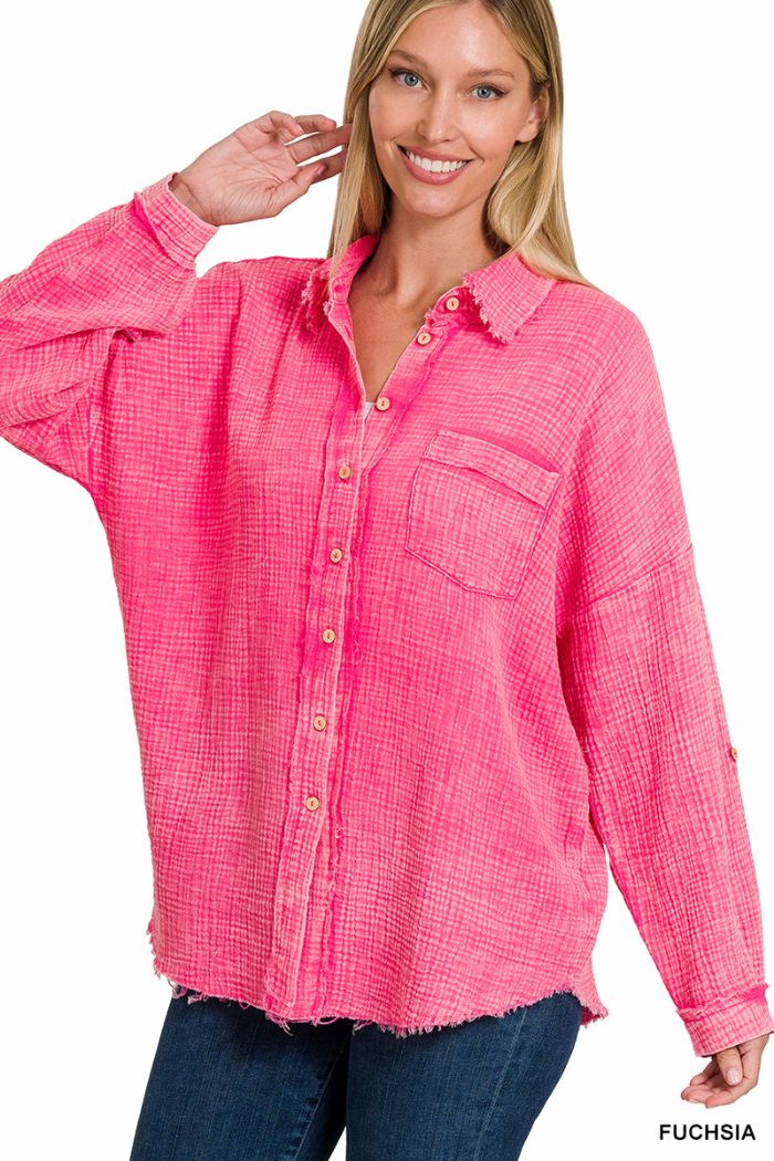 A smiling woman with long blonde hair wears a Washed Double Gauze Shirt by Zenana in bright fuchsia, featuring one chest pocket and rolled sleeves, paired with dark blue jeans.