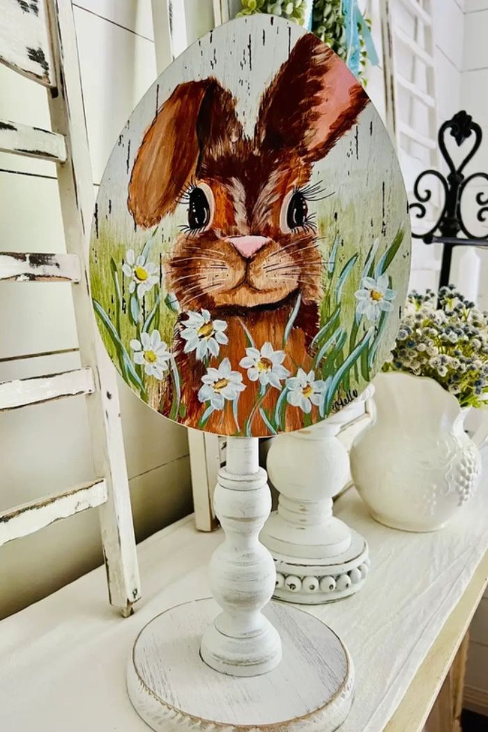 The Spring Summer Wood Toppers feature a decorative wooden egg with a brown bunny and white daisies, displayed on a white stand, making it a charming addition to your seasonal table and vintage-inspired home décor.
