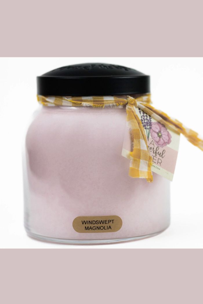 The Papa 34oz Candle features pale pink scented wax in a decorative jar with a black lid and yellow plaid ribbon. A WINDSWEPT MAGNOLIA label and charming tag complete this beautiful centerpiece.