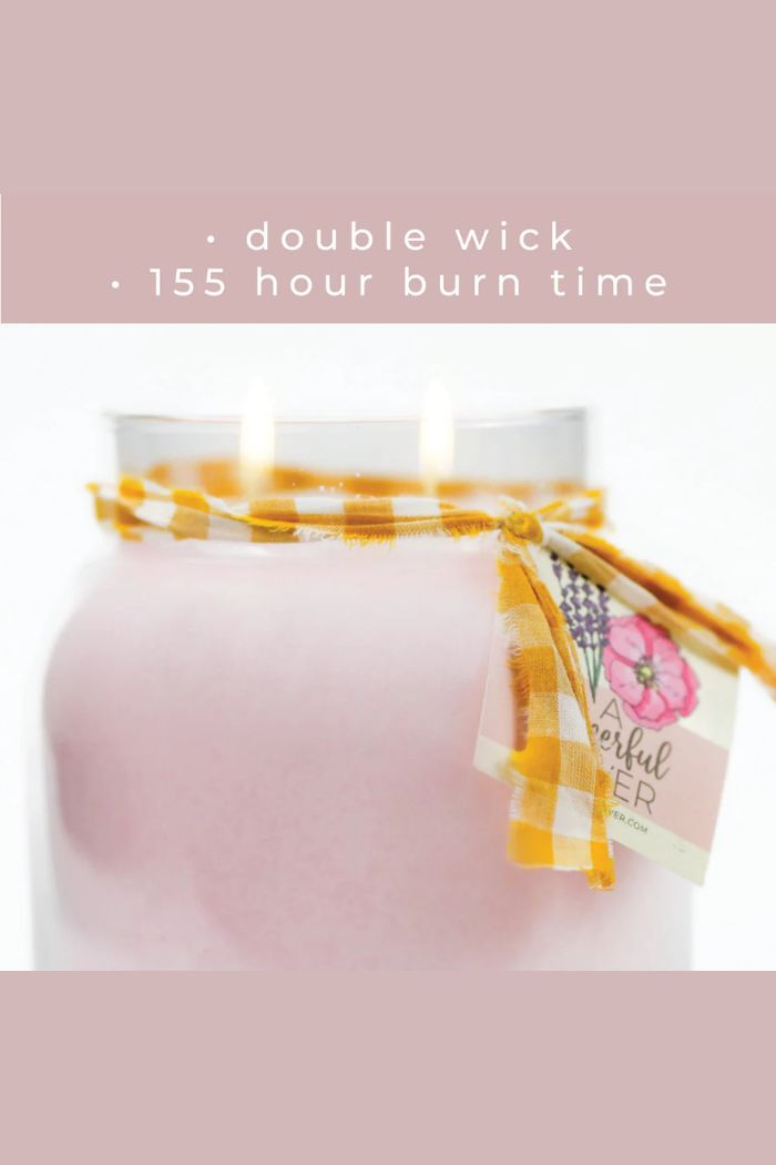 The Papa 34oz Candle is a large scented candle with two wicks, wrapped in a yellow and white plaid ribbon and a floral tag. Text above says: double wick • 155 hour burn time • 34oz candle.
