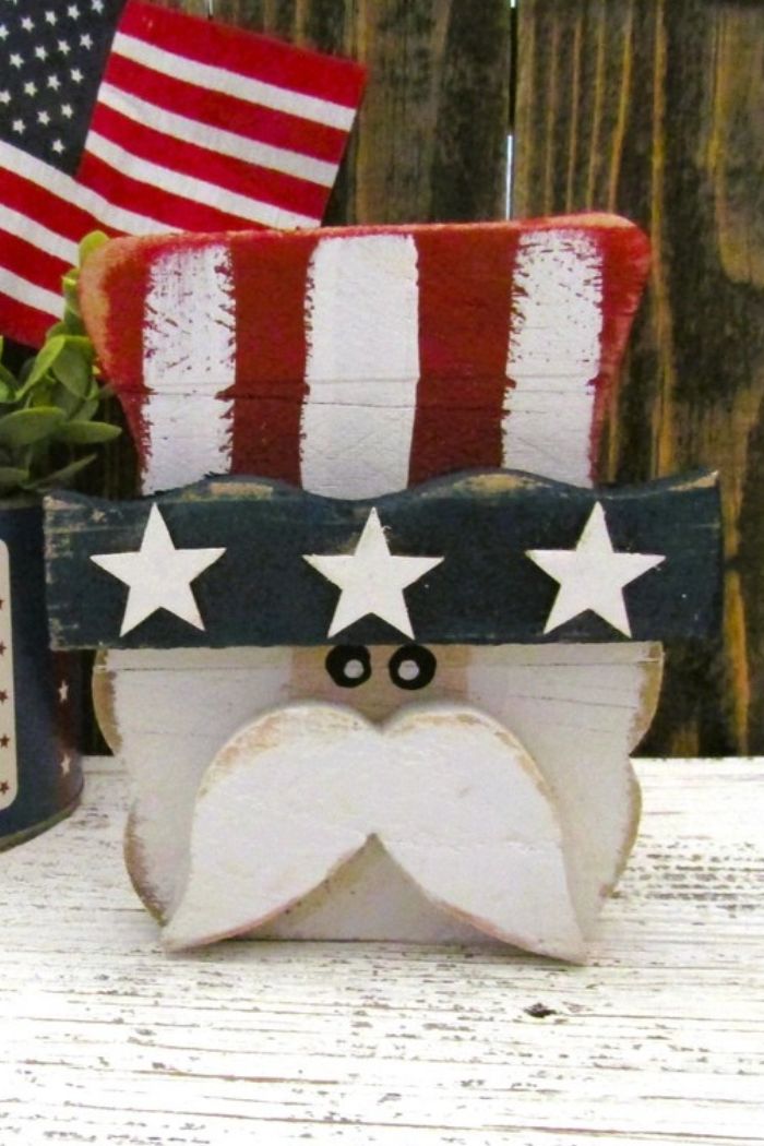 Rustic Uncle Sam Decor features a red, white, and blue striped hat with white stars on a blue band and a white mustache—ideal farmhouse patriotic decor with an American flag background.