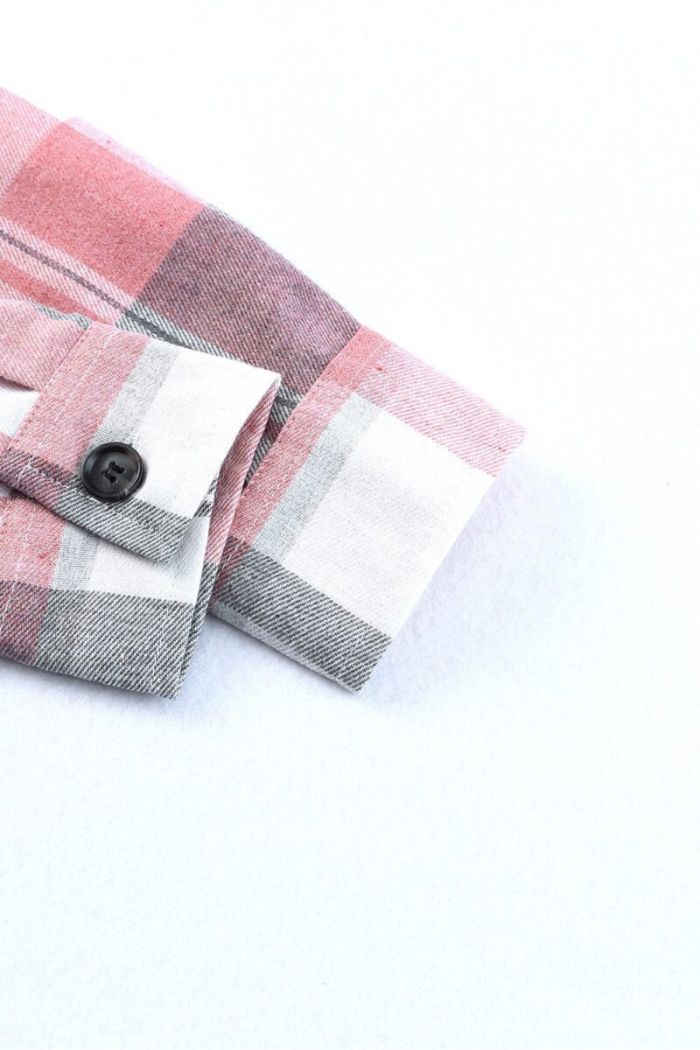 A close-up of the sleeve cuff of the Plaid Button Up Shirt in pink, gray, and white, showcasing a black button against a plain white background.