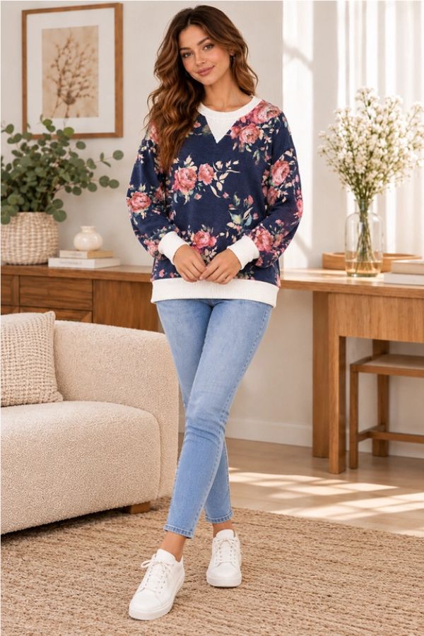 A woman wears a relaxed fit navy blue Floral Ribbed Sweatshirt with white ribbed trim at the neckline and cuffs, paired with light-wash jeans and white sneakers.