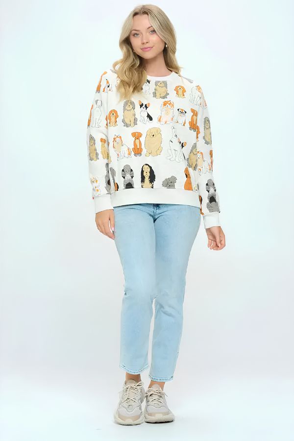 A woman stands against a plain white background wearing the Dog Print Crewneck Sweatshirt featuring colorful dog illustrations, paired with light blue jeans and beige sneakers—a perfect look for dog lovers.