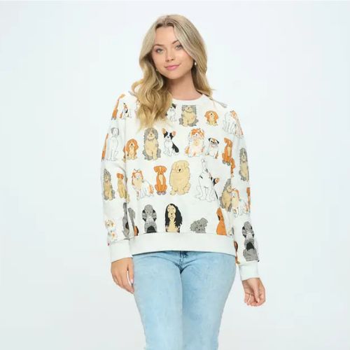A woman stands facing forward against a plain light background, wearing the Dog Print Crewneck Sweatshirt featuring colorful cartoon dog illustrations, paired with light blue jeans and her loose, wavy blonde hair—making it a perfect gift for dog lovers.