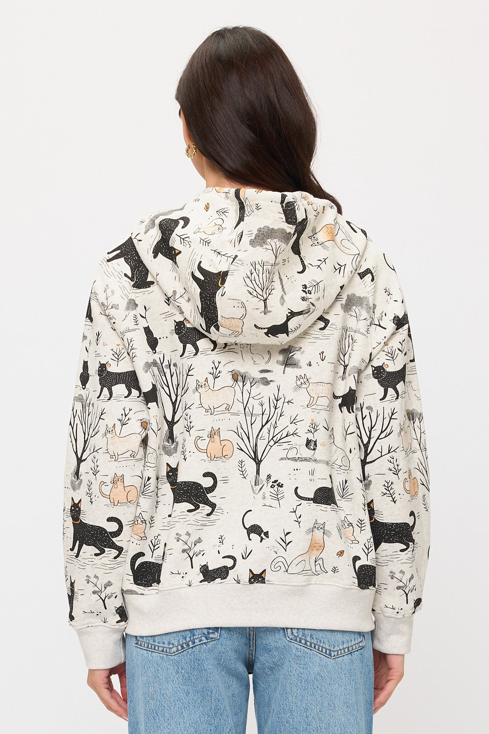 Someone with long brown hair is seen from behind wearing the Cat Forest Zip Hoodie, featuring a cozy fit and cat and forest print, paired with light blue jeans.