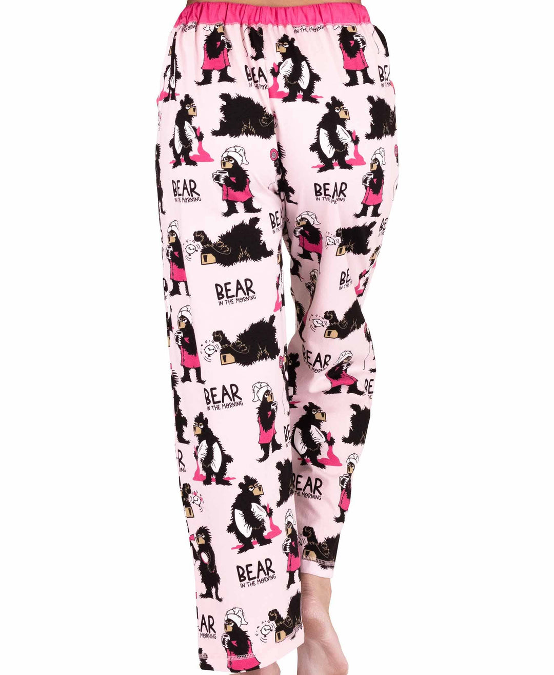 Model wears the Dog Mom, Cat Nap & More Pajama Pants featuring a light pink color, cartoon bear and woman print with "BEAR in the morning" text, plus coordinated pink waistband and accents.
