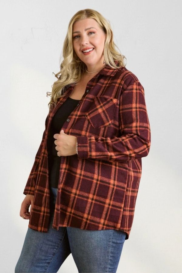 A person wearing a maroon and orange Curvy Plaid Flannel Shirt over a black top and blue jeans.