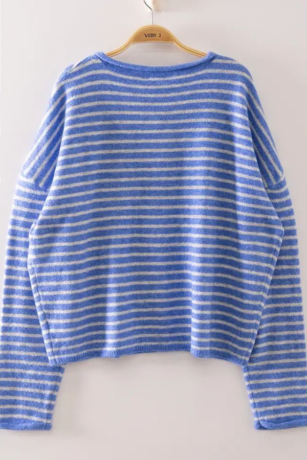 The Striped Button Front Sweater, featuring soft blue and white horizontal stripes in an oversized fit, hangs on a wooden hanger against a plain light background.