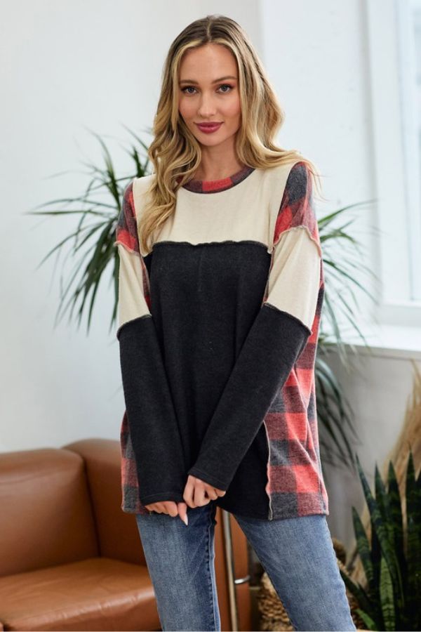 A woman wearing a Vintage Plaid Colorblock Pullover with red plaid panels and a solid dark gray center panel.