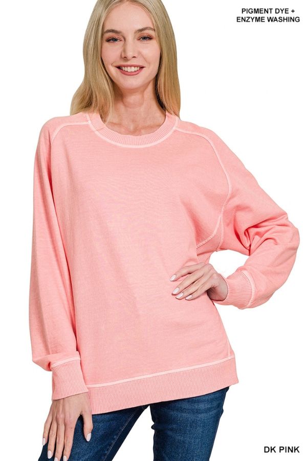 A person wears a relaxed fit, enzyme-washed light pink Pigment Dye French Terry Sweatshirt with ribbed trim and visible seams, featuring text in the corner reading PIGMENT DYE + ENZYME WASHING and DK PINK at the bottom.