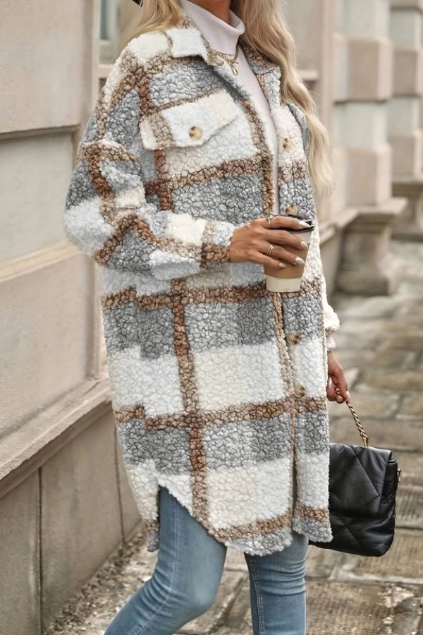 A person wearing a long, plaid Plaid Teddy Fleece Coat with button closures, holding a coffee cup and a black handbag.