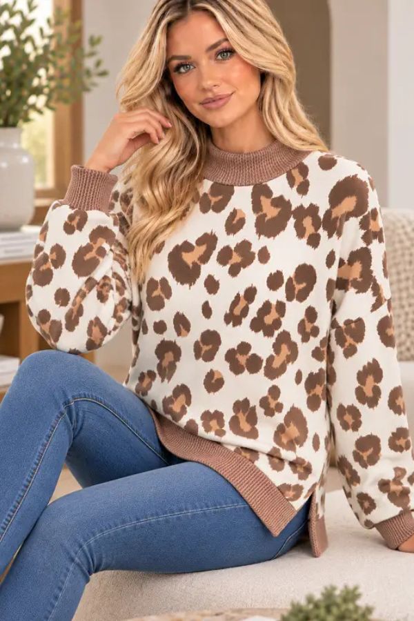 A woman wears a cream, brown, and tan Leopard Print Mock Neck Sweatshirt in a relaxed fit, finished with ribbed cuffs and hem.