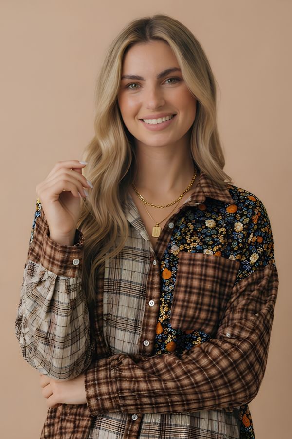 A smiling woman with long, wavy blonde hair models the Curvy Patchwork Button Down Top, showcasing its mix of plaid and floral patterns styled as an ideal fall layering piece with a gold necklace, set against a plain beige background.