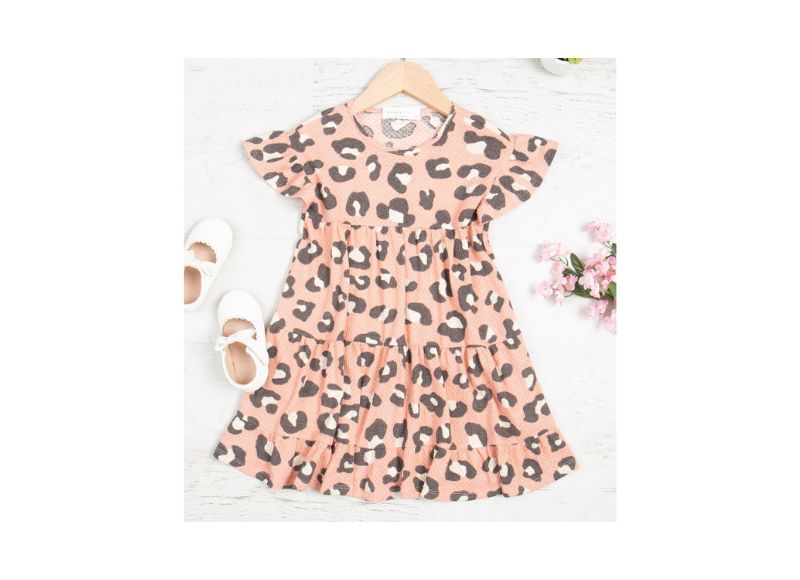 Pink dress with leopard print on a hanger against a white background