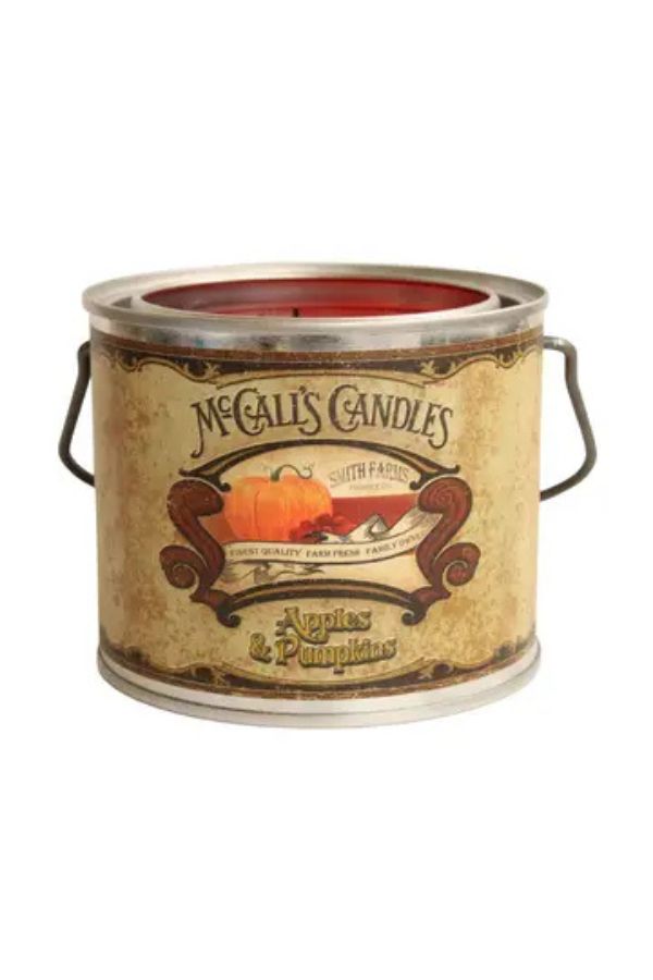 A McCall’s Moving Flame Candle tin labeled Apples &amp; Pumpkins, featuring an illustration of apples and a pumpkin, with side handles and a vintage-style design. This charming wax candle fills your space with inviting fall scents, perfect for creating a cozy autumn atmosphere.