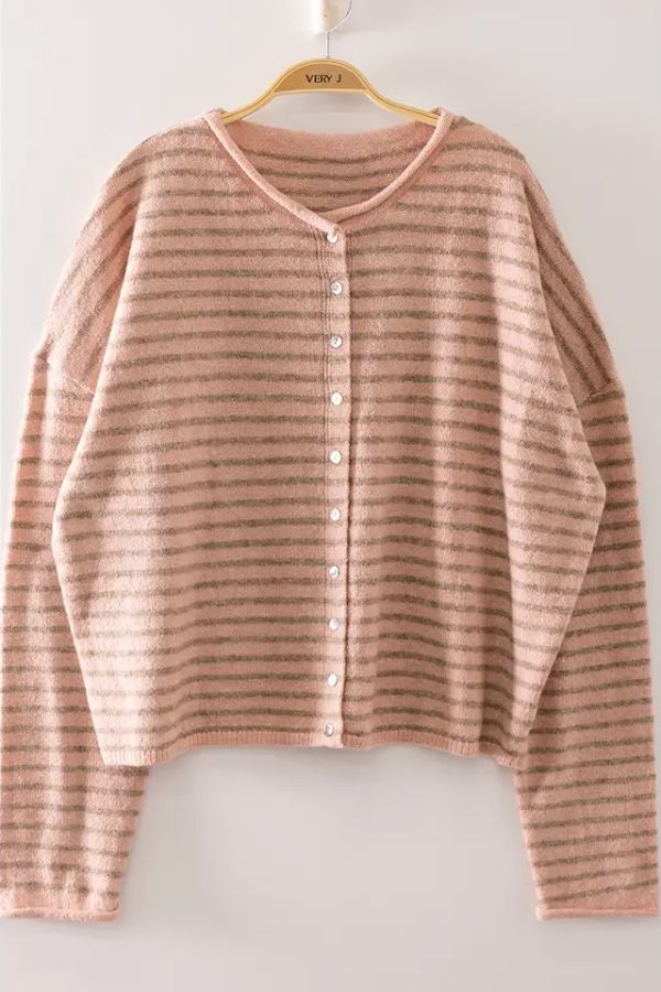 The Striped Button Front Sweater, featuring soft long sleeves and light pink and gray horizontal stripes, hangs on a hanger against a plain white wall—perfect for anyone looking for a cozy knit cardigan.
