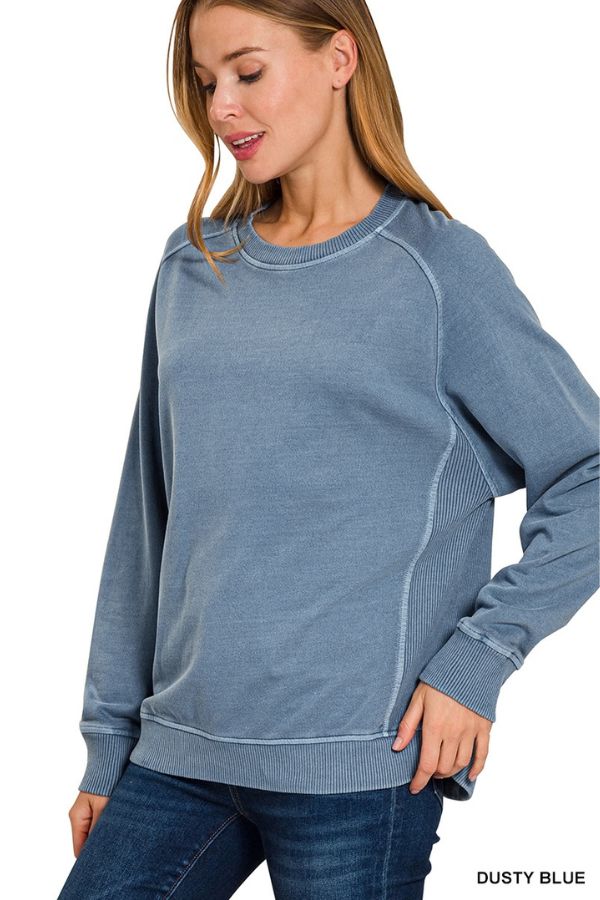 A woman wears a dusty blue Pigment Dye French Terry Sweatshirt in a relaxed fit with ribbed side panels and cuffs.