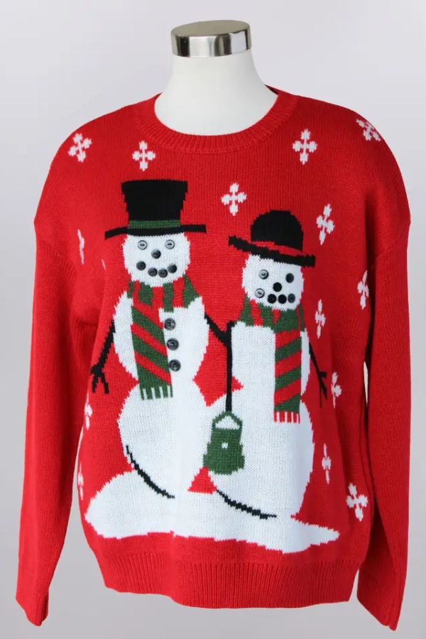 The Snowman Christmas Knit Sweater is a festive red holiday sweater featuring two snowmen with black hats, striped scarves, and buttons, holding hands amid small white snowflakes.