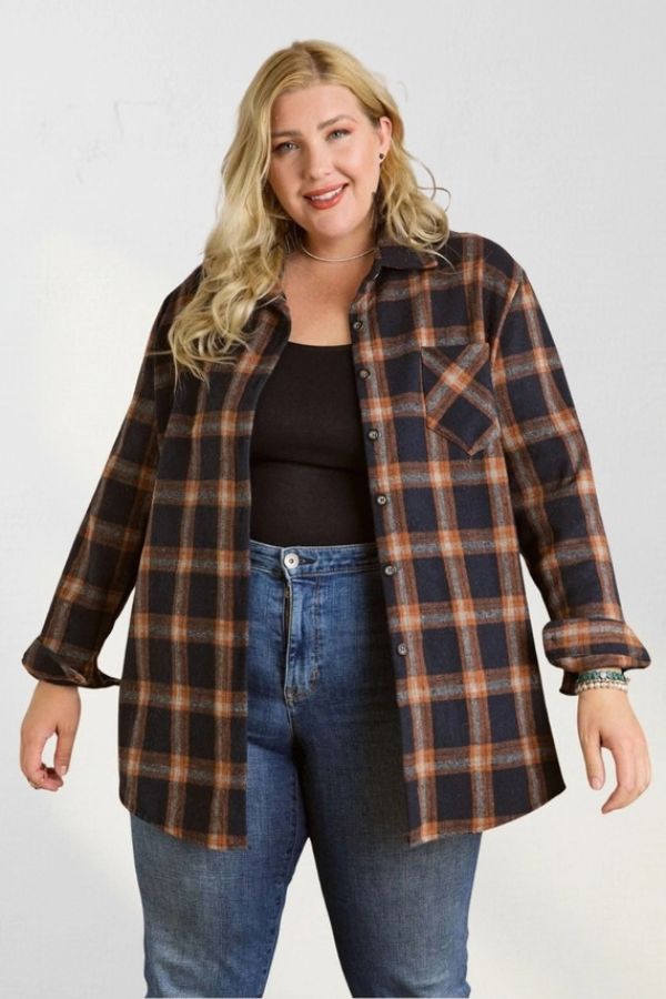 A woman wearing an oversized Curvy Plaid Flannel Shirt unbuttoned over a black tank top and blue jeans.