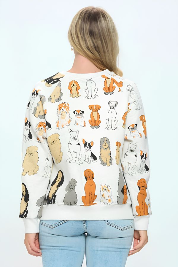 Wearing the Dog Print Crewneck Sweatshirt featuring vibrant cartoon dog illustrations on a white background, a woman stands with her back to the camera, highlighting the playful design. This cozy top is ideal for dog lovers and is styled with light blue jeans, while her shoulder-length blonde hair adds to the laid-back vibe.