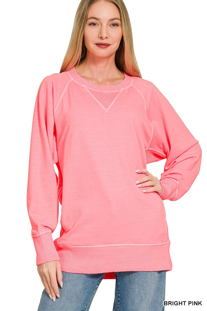 A woman wearing a bright pink Pigment Dyed Pullover and blue jeans stands with one hand on her hip, smiling at the camera.