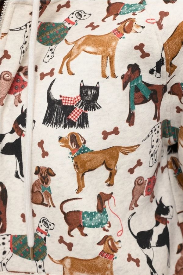 Illustration of various dog breeds wearing scarves and sweaters, with scattered bone shapes on a cream-colored fabric—perfect for the Holiday Dogs Zip Up Hoodie that dog lovers will cherish.