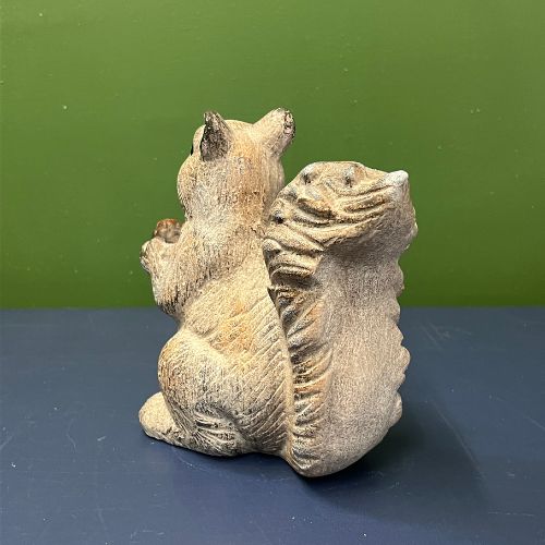 The Scamper Squirrel Figurine, crafted from brown ceramic and shown from behind, rests on a dark blue surface against a green background—an adorable addition to farmhouse décor and fall decorating.