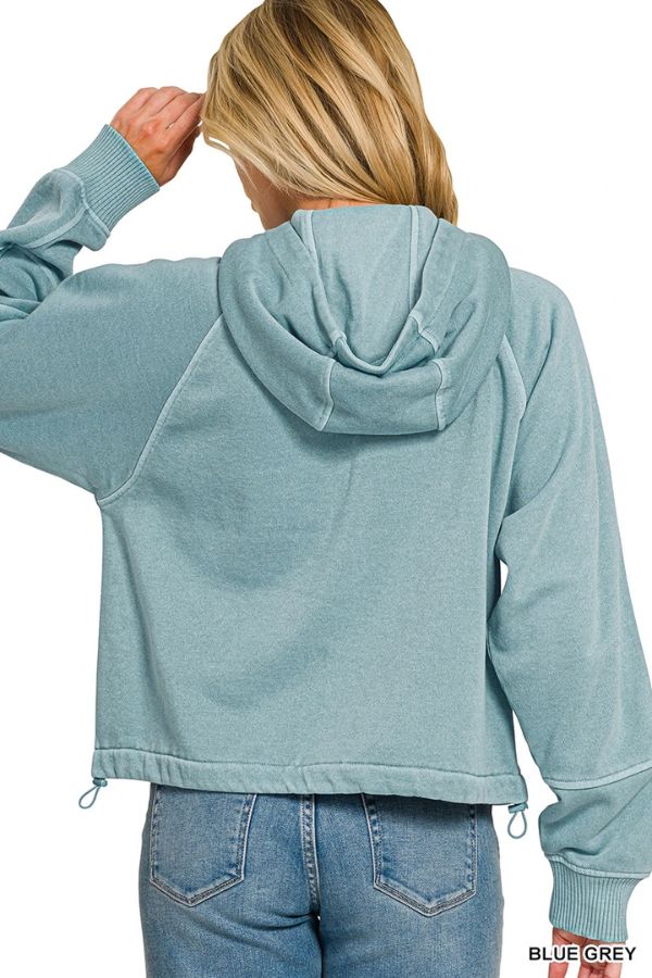 A person wearing the Pigment Dye Zip Up Hoodie in blue-grey and blue jeans stands with their back to the camera, one hand touching their head.