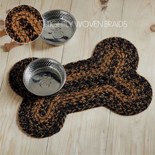 The Braided Bone Shaped Rug features tightly woven black and brown braids and holds two silver pet bowls. This durable braided construction dog rug is shown on a light wooden floor with dog treats nearby.