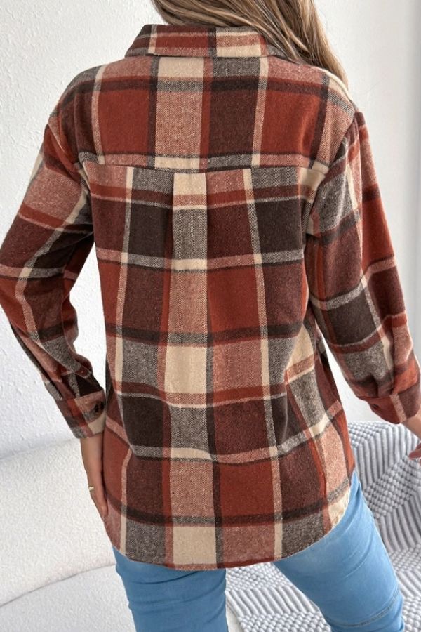 A person wearing the Rust Plaid Longline Coat, featuring a brown, beige, and red plaid pattern with a longline silhouette, stands with their back to the camera. They have long hair and are also wearing light blue jeans, creating an effortlessly lightweight layered look.