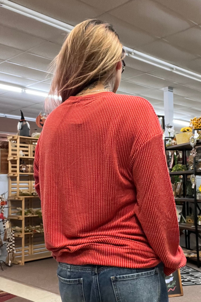 A person wearing a red ribbed long-sleeved shirt, viewed from the back.