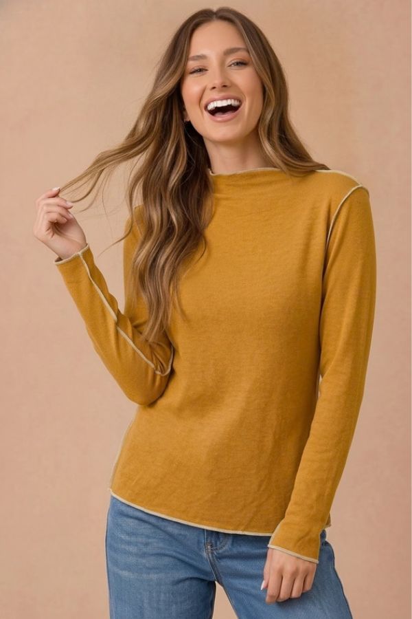 Woman wearing a mustard yellow Curvy Frilled Mock Neck Hacci Top with exposed seams.
