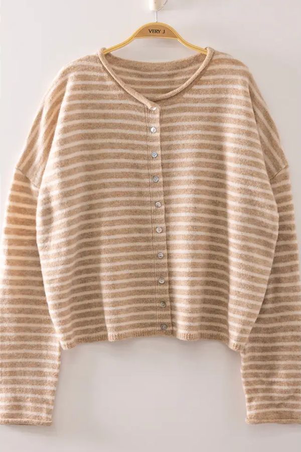 A Striped Button Front Sweater in beige and white hangs on a wooden hanger against a simple light background, displaying the timeless charm of this cozy knit cardigan.