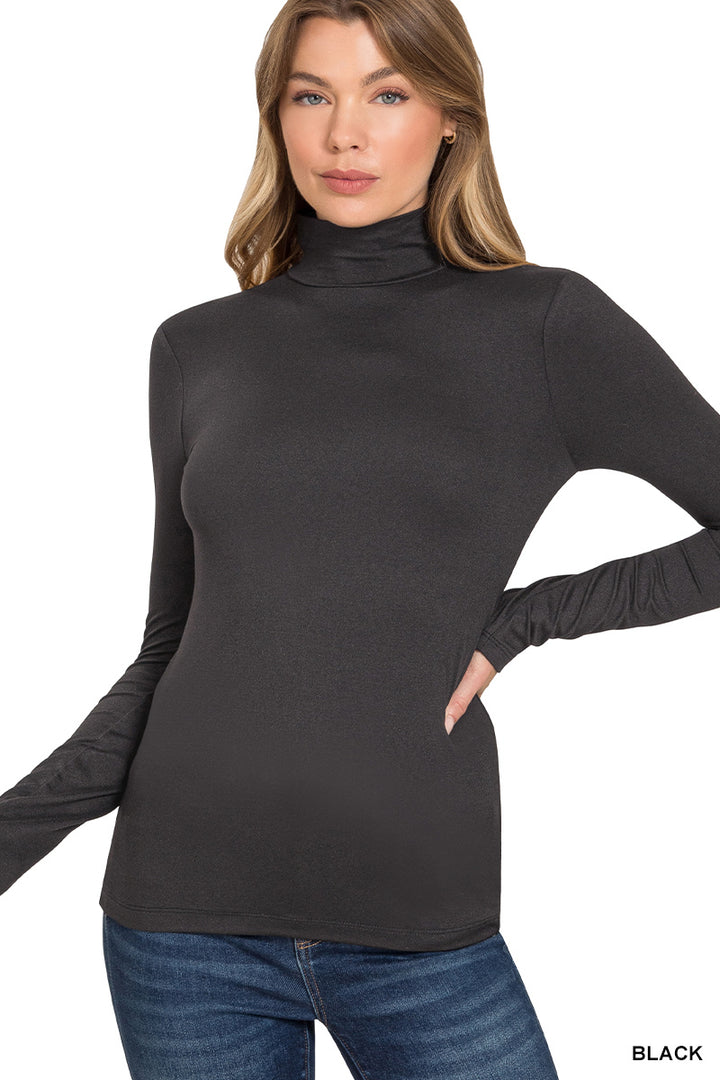 A woman poses with one hand on her hip against a plain white background, showcasing the Lightweight Mock Neck Shirt in black paired with blue jeans for an effortlessly chic workwear look.