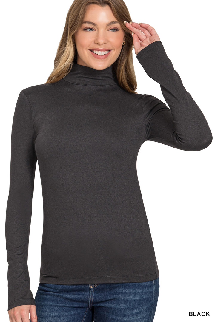 A smiling woman wears the Lightweight Mock Neck Shirt with jeans, standing with one hand raised near her head against a white background—an effortlessly polished long-sleeve top ideal for workwear or everyday style.