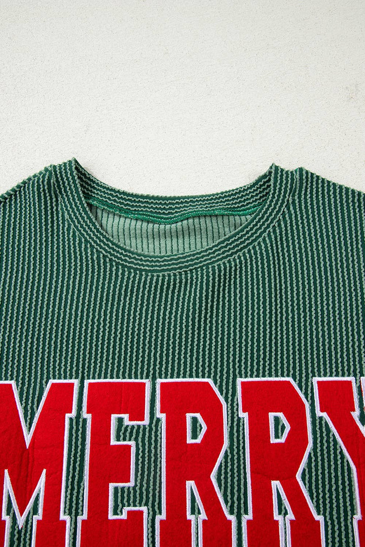 The Merry Graphic Top features green and white stripes with large red “MERRY” lettering across the chest, making it a perfect festive sweater for holiday gatherings and cozy winter days, shown here against a light background.