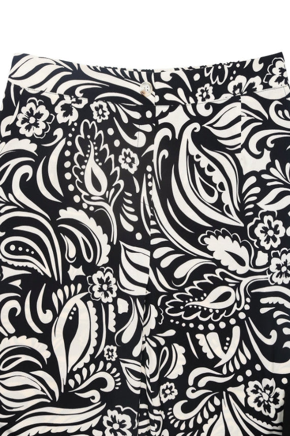 Close-up of Boho Wide Leg Pants showing a bold white floral paisley print, high-rise elastic waistband, and classic button and zipper closure.