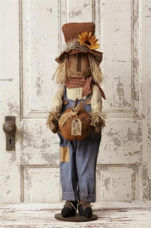 Scarecrow standing holding pumpkin